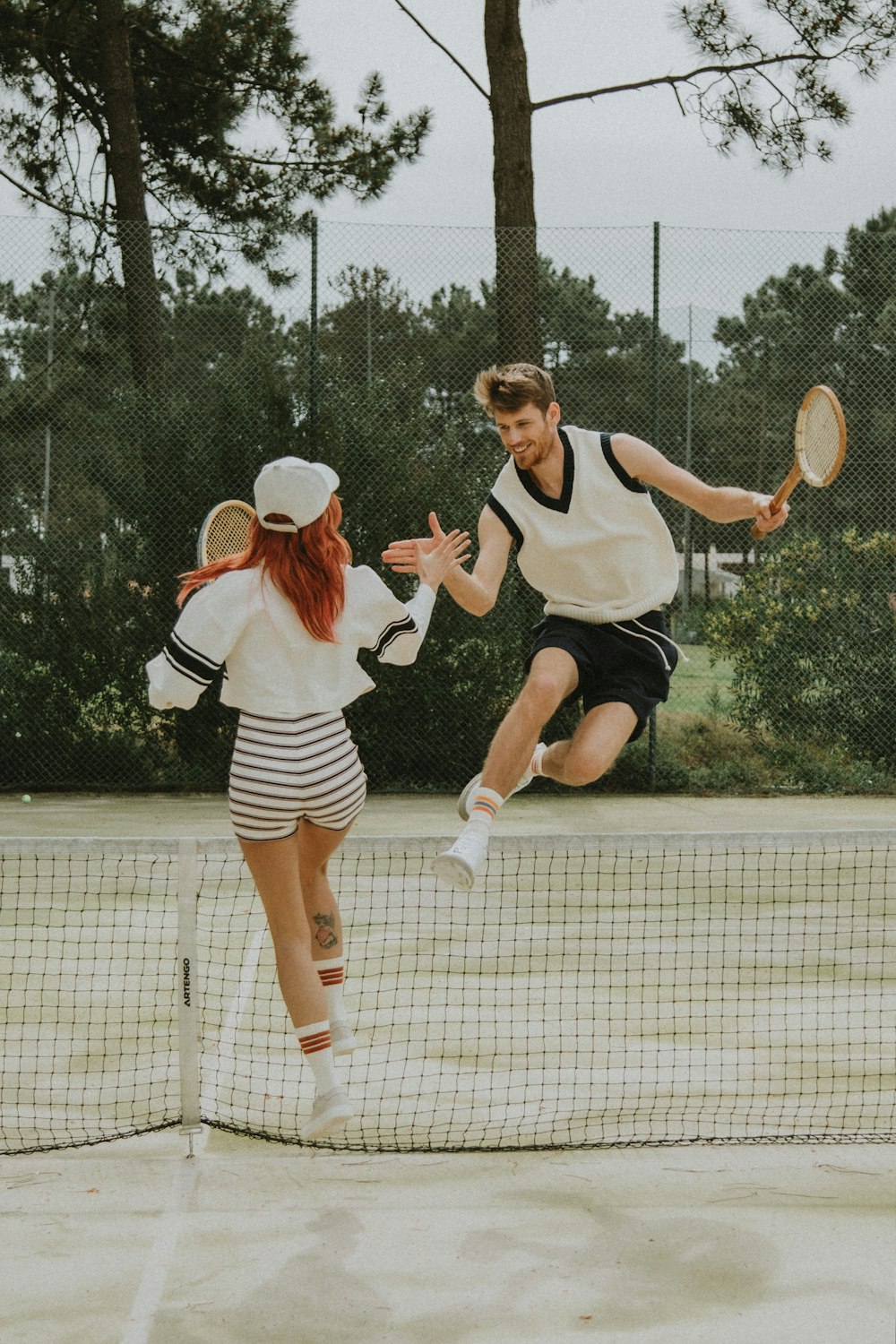 2 Frauen in weiß-schwarzem Kleid mit Tennisschläger