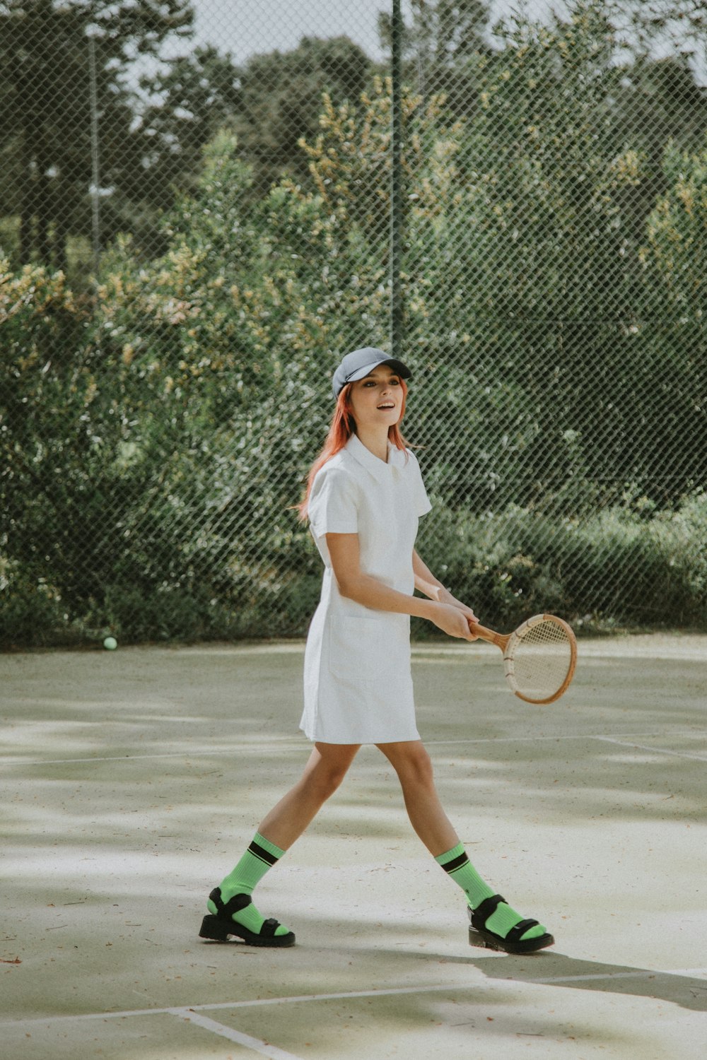 Mujer con camisa blanca de manga larga y falda blanca sosteniendo raqueta de tenis
