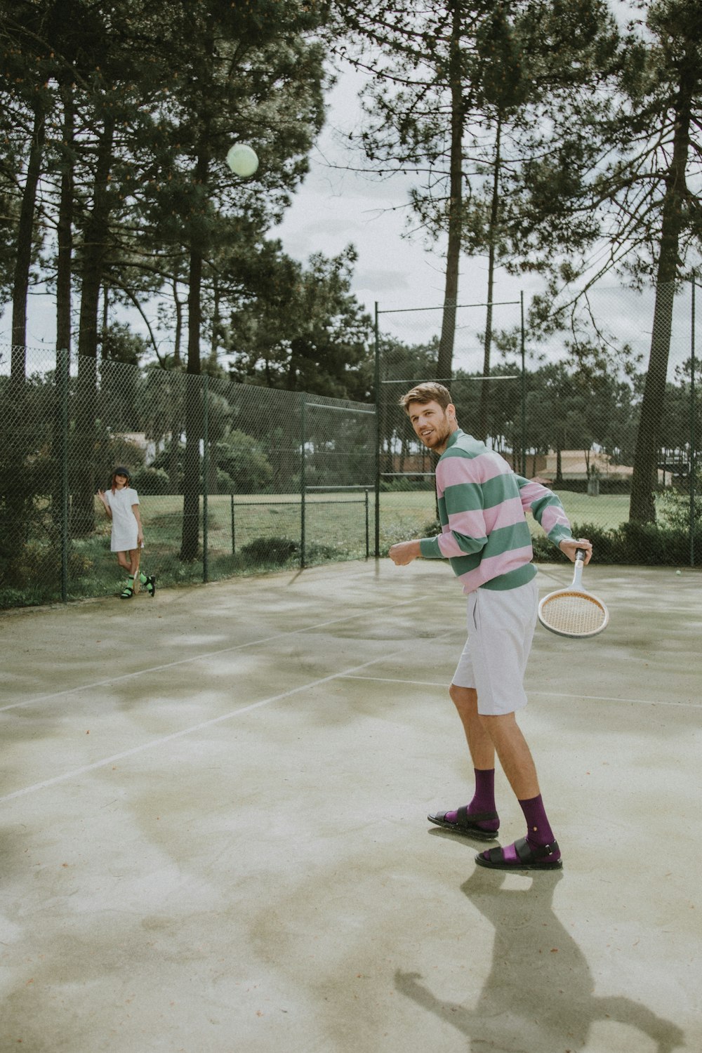 man in white and green crew neck t-shirt and black shorts holding tennis racket
