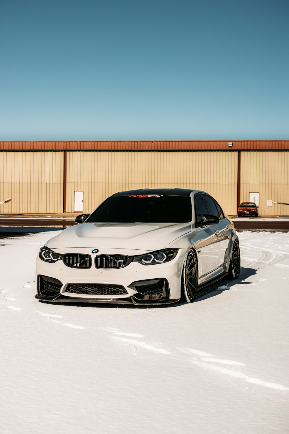 BMW M 3 Coupé blanco aparcado en suelo cubierto de nieve durante el día