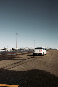 A sleek Hertz rental car parked outside Atlanta International Airport under a bright sky.