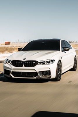 White BMW M5 on open road with clear bright headlights