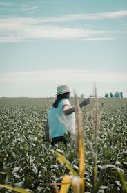 man in green and white plaid dress shirt and brown hat standing on green grass field