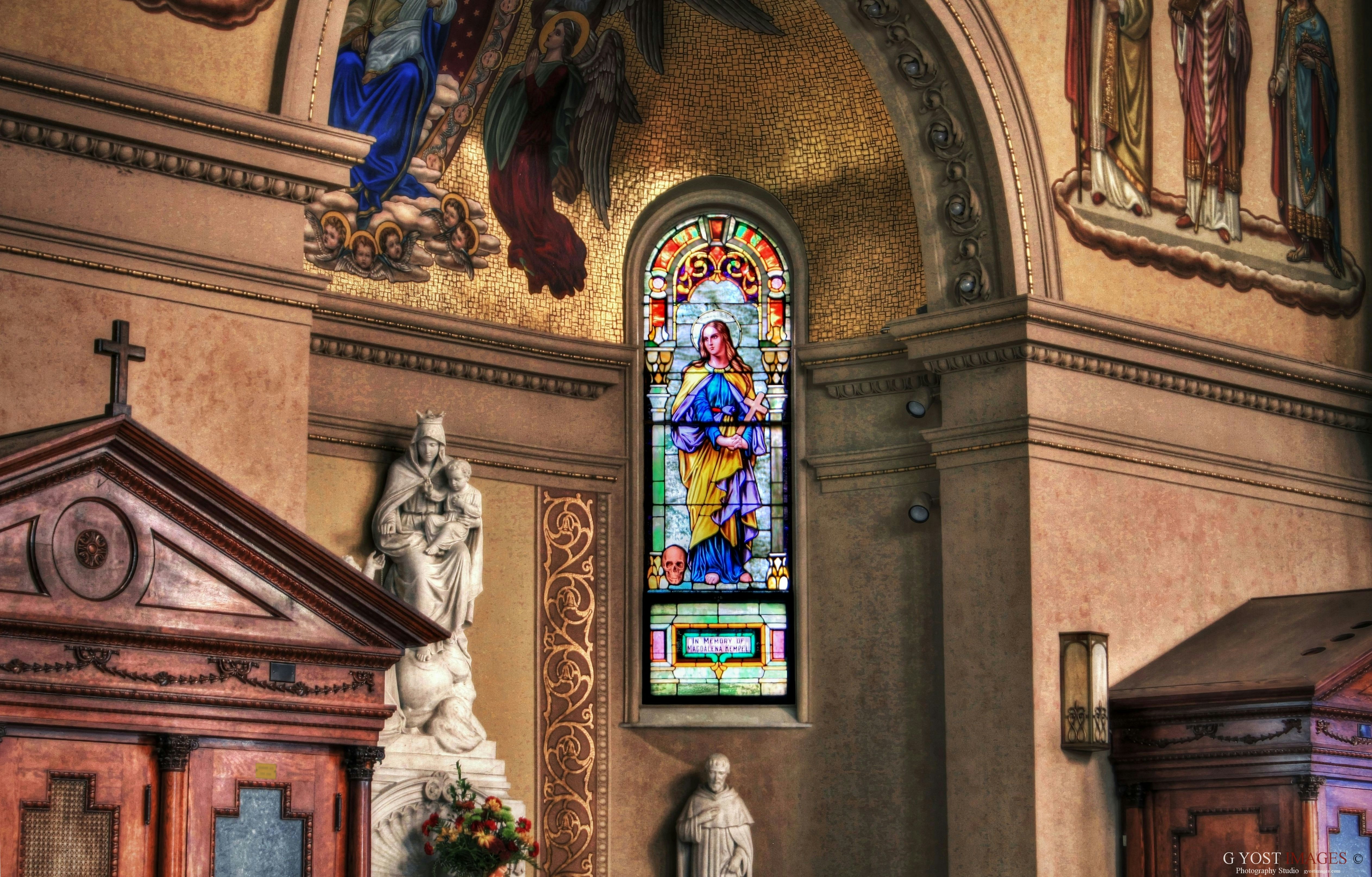 white statue in front of brown concrete building, Beautiful stained glass window of a catholic church.