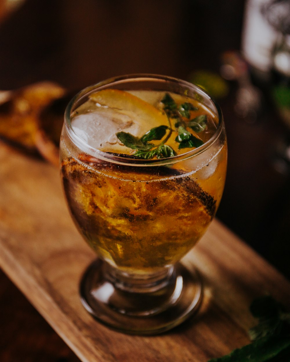 Bicchiere trasparente con liquido marrone e foglie verdi