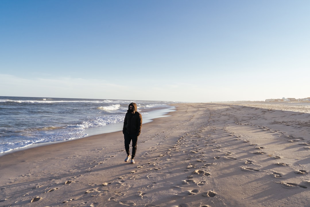 woman in black coat standing on beach during daytime