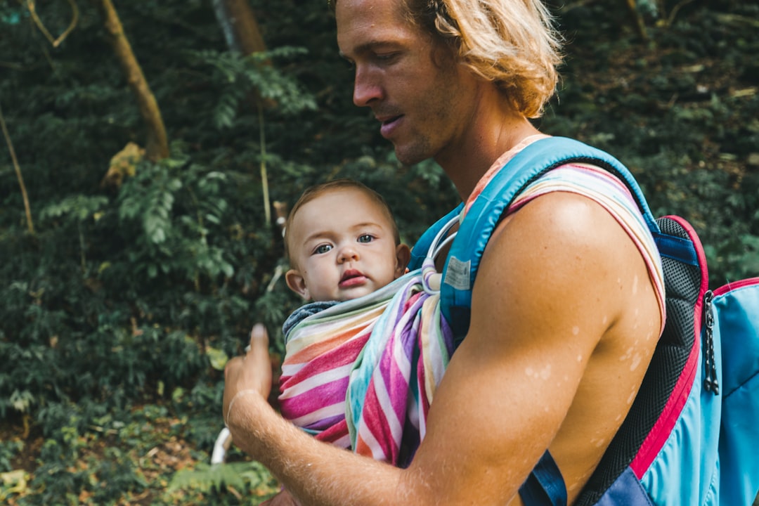 woman in blue tank top carrying baby in pink and white stripe shirt