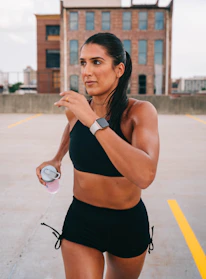 Woman in neon green sportswear running outdoors with city skyline in background