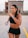 A smiling woman holding a fitness tracker while jogging outdoors.