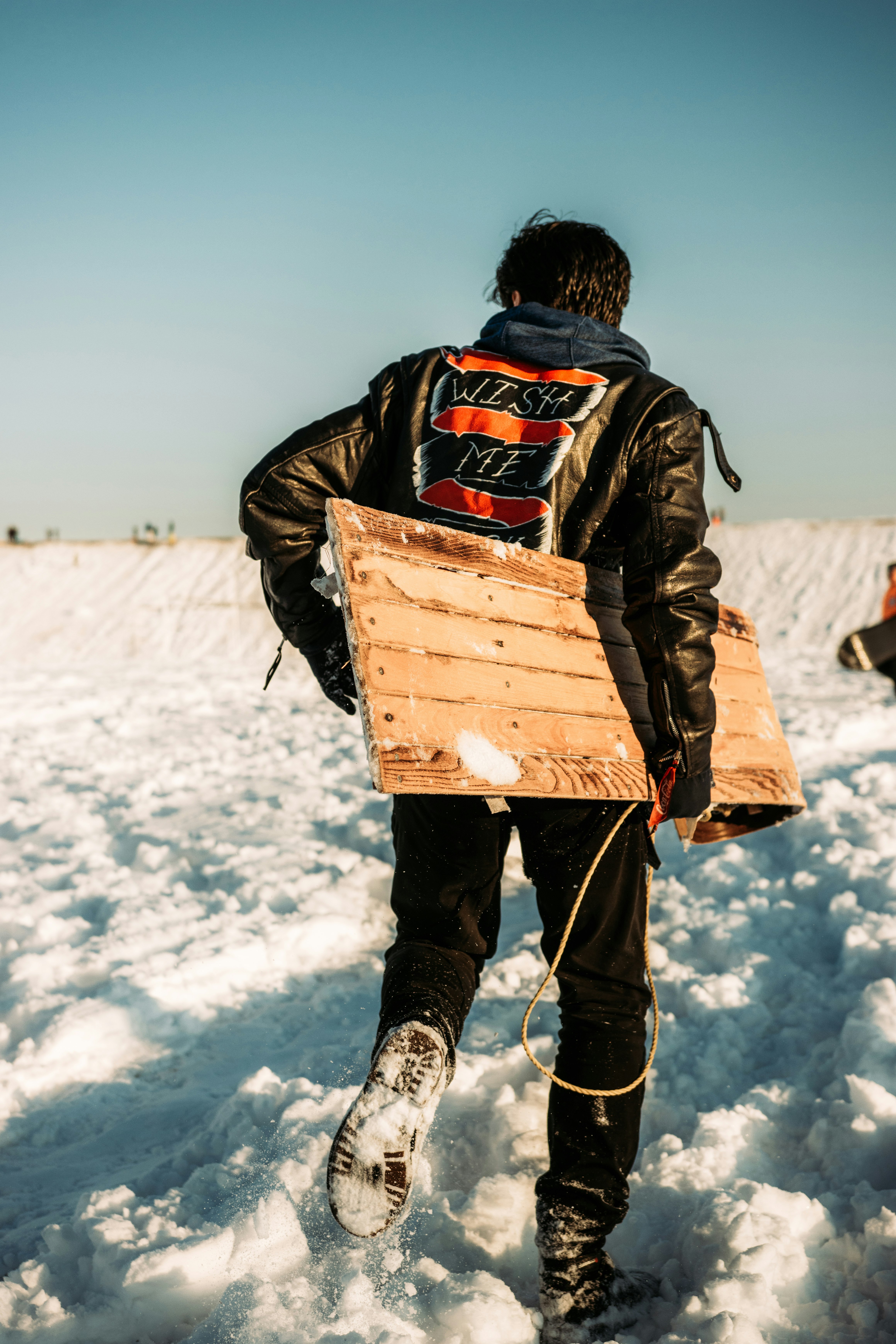 person in black jacket carrying brown wooden box on snow covered ground during daytime