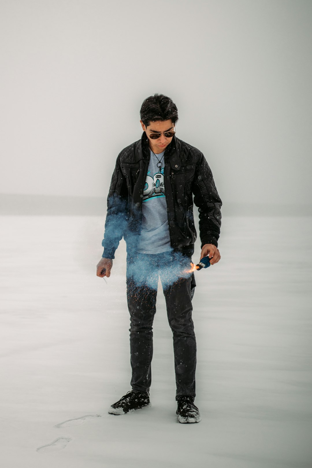 man in black leather jacket and blue denim jeans standing on snow covered ground
