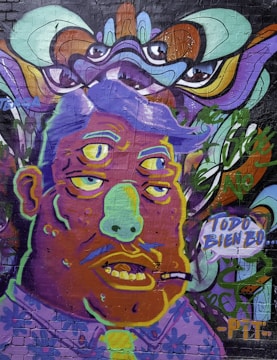 A vivid and surreal mural depicting a character with three eyes and exaggerated facial features. The art style is psychedelic and cartoonish, with bold outlines and a colorful palette. Above, abstract patterns and eyes add a sense of mystery. The character has a cigarette in its mouth, and a speech bubble containing Spanish text, 'TODO BIEN BO'.