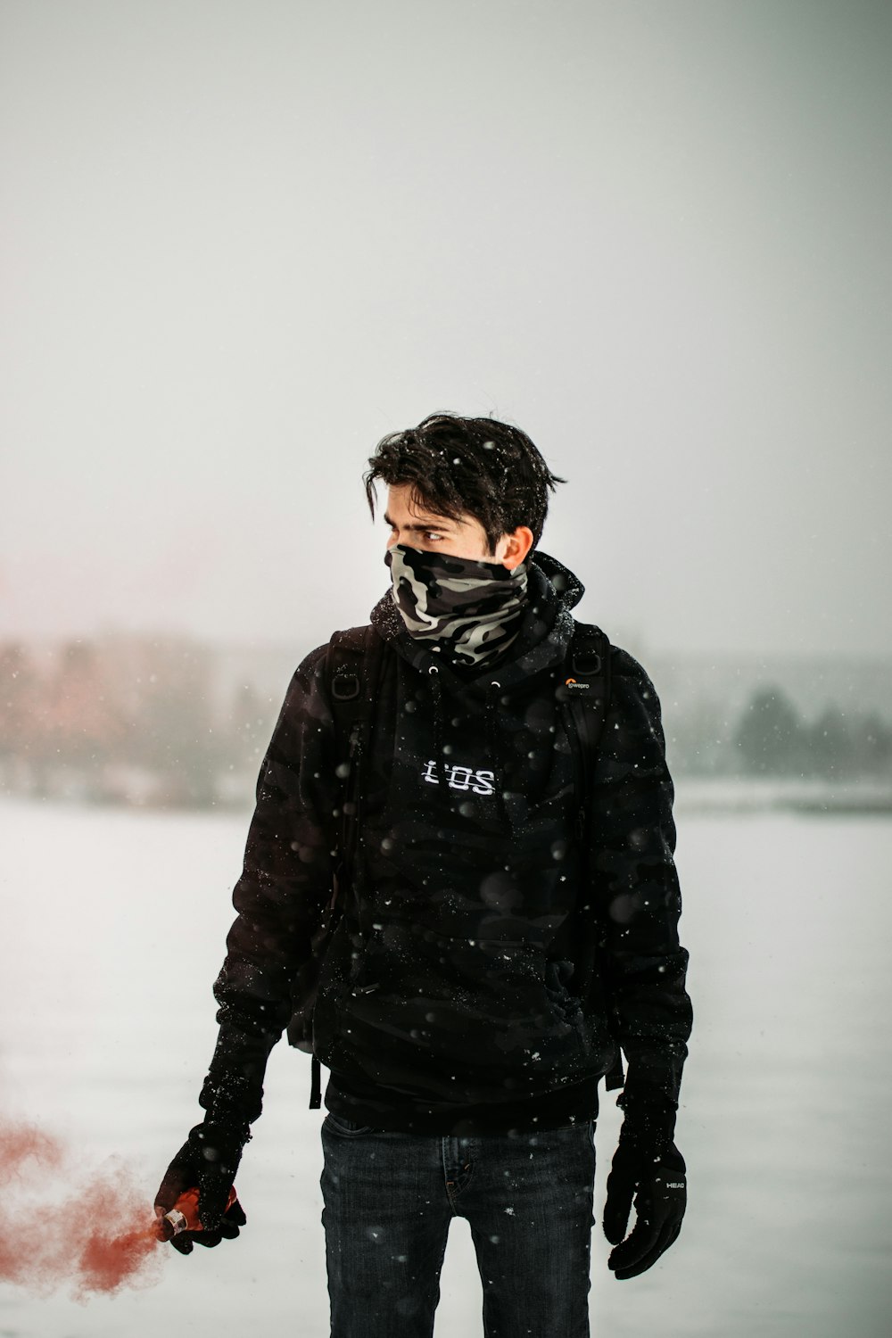 雪に覆われた地面に立つ黒いジャケットと黒いリュックサックの男