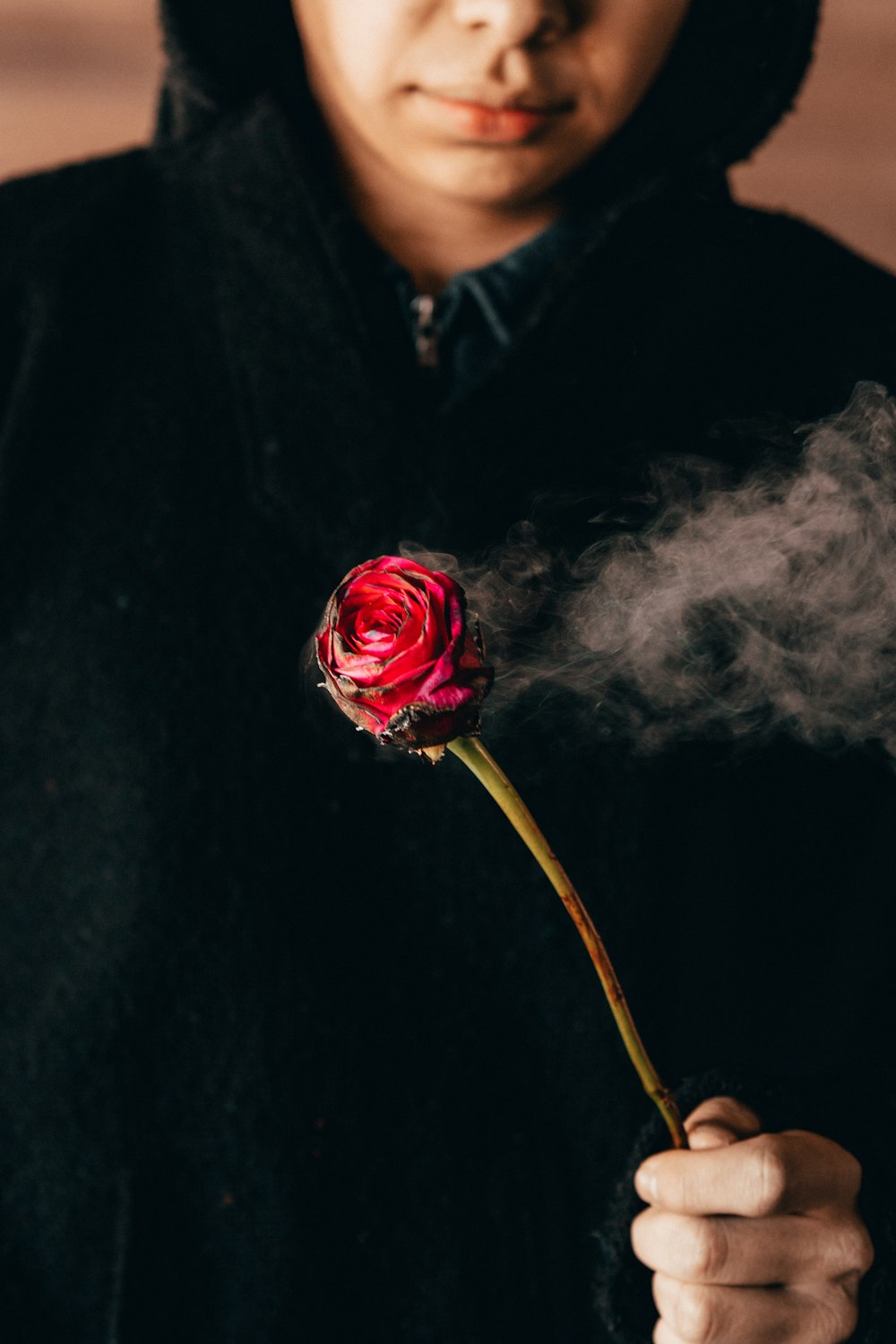 person in black shirt holding red rose