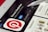 A close-up of a tablet screen displaying the Pinterest app page on a digital store, with the Pinterest logo prominently featured. A white stylus is resting on the screen, which also shows app details like stars rating and install button.