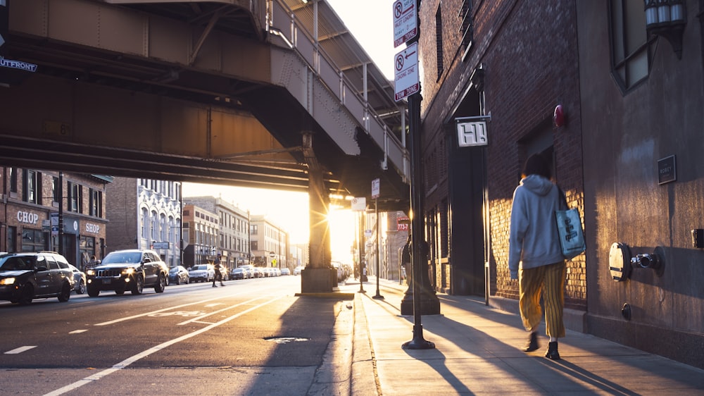 man in blue jacket walking on sidewalk during daytime