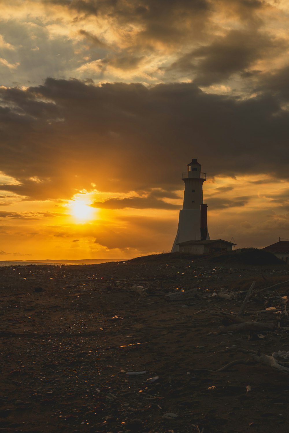 夕暮れ時の茶色の砂浜の白い灯台