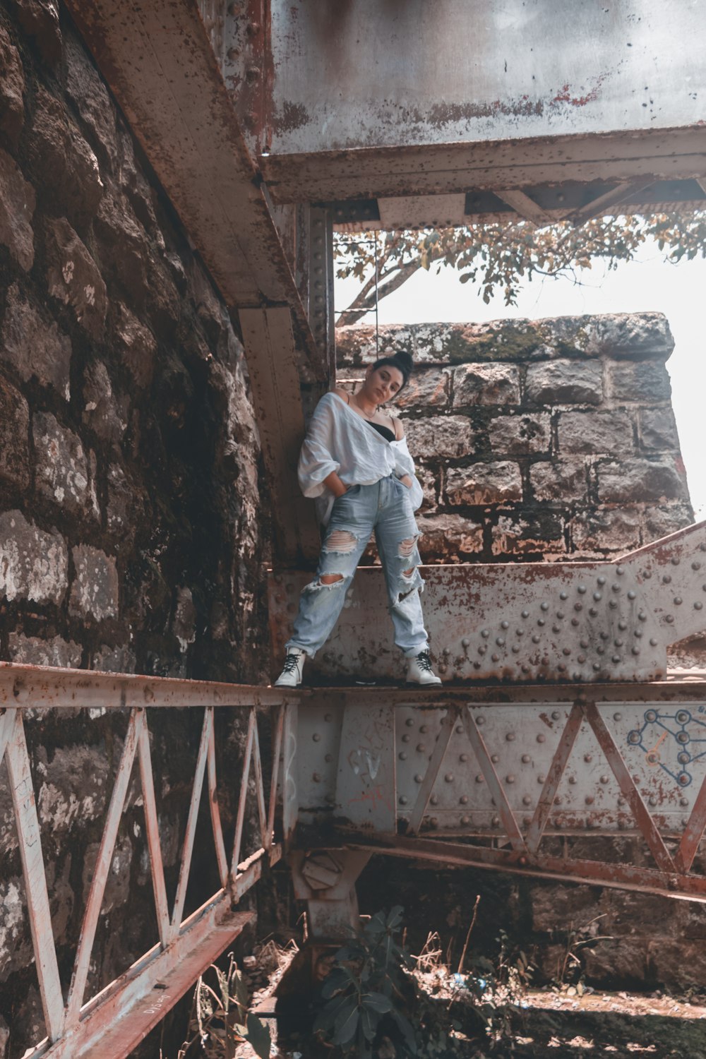 man in white dress shirt and blue denim jeans standing on brown concrete stairs during daytime