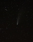 An artistic shot of a comet streaking across a dark sky dotted with countless stars