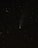 A night sky filled with numerous stars and a prominent visible comet with a glowing tail. There is also a faint streak of light, possibly a meteor, crossing the upper left of the image.