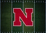 A large red letter 'N' with a white outline is centered on a green football field with white yard lines.