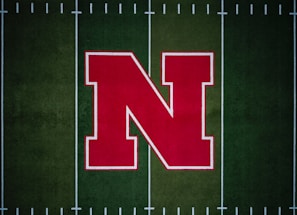 A large red letter 'N' with a white outline is centered on a green football field with white yard lines.