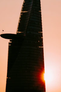 A sleek office tower representing modern banking, set against the Baghdad skyline at dusk with warm golden lighting.