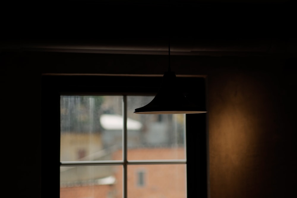 black pendant lamp turned on near glass window