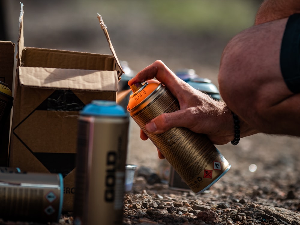 person holding orange and silver can