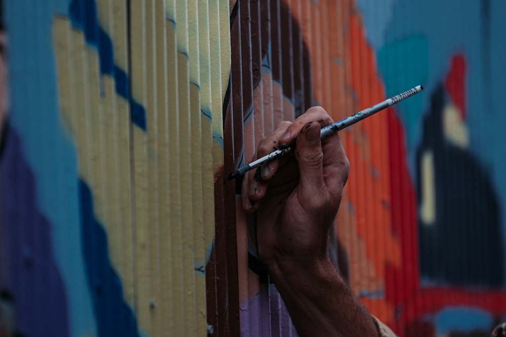 Persona sosteniendo un tubo plateado cerca de una pared marrón