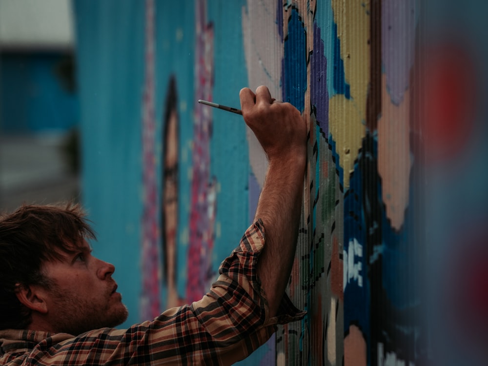 man in brown and black plaid shirt painting on wall