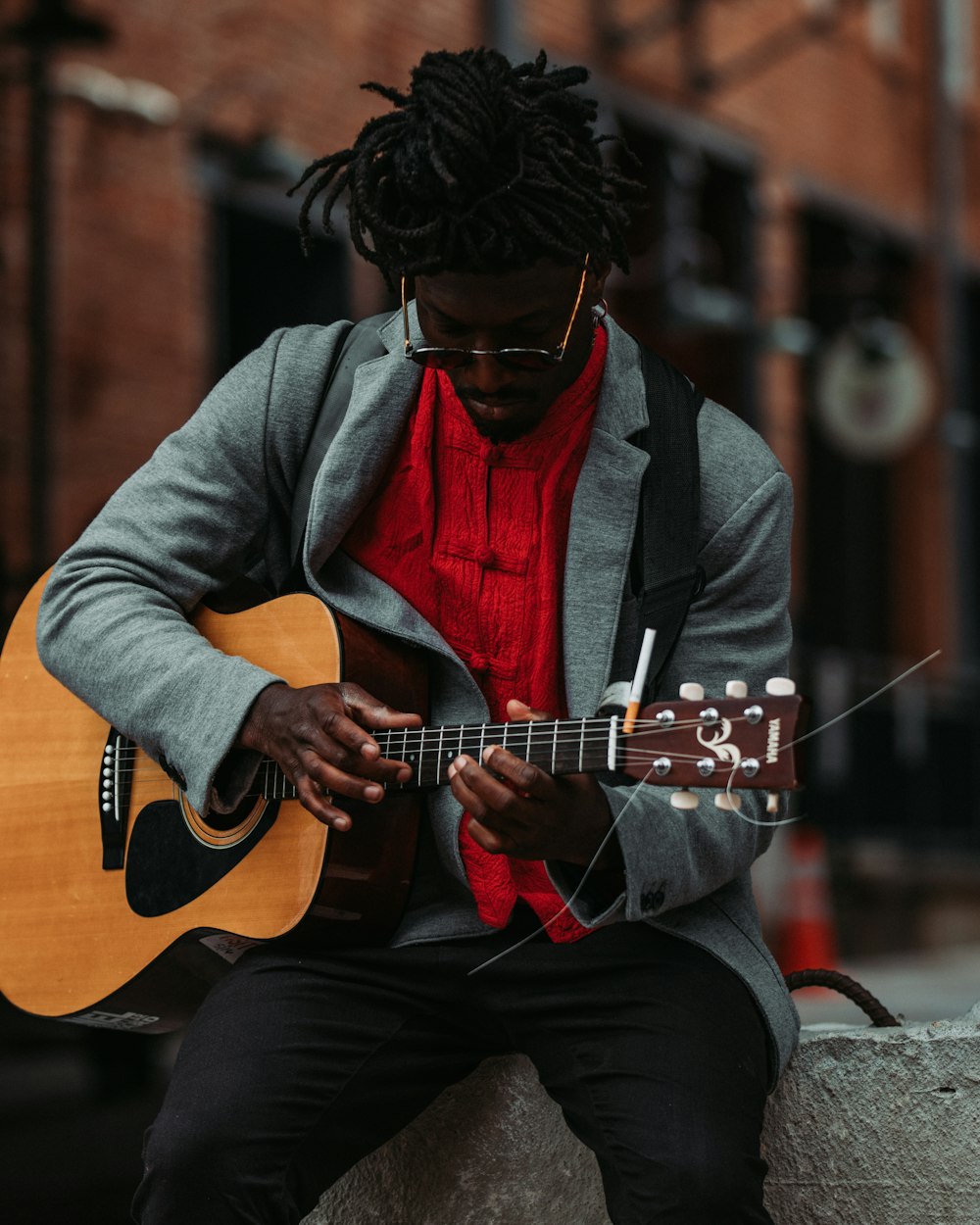 man in gray and black zip up jacket playing brown acoustic guitar