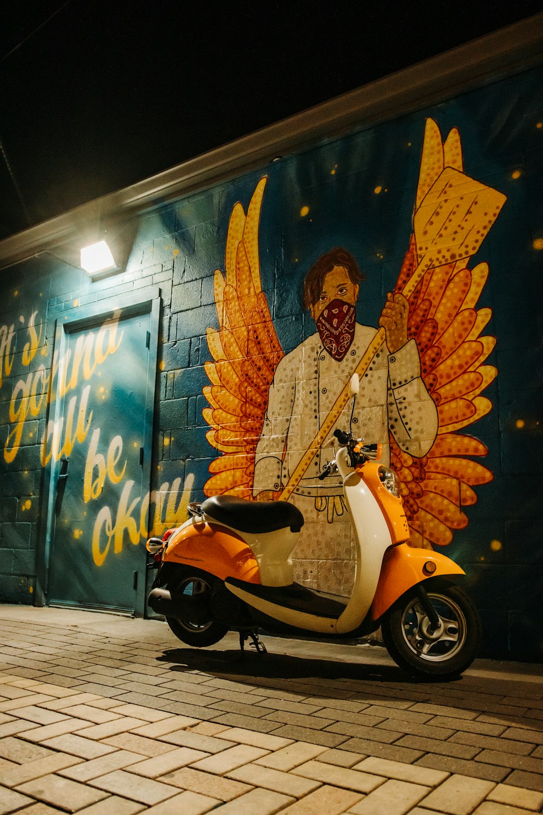 man in orange jacket riding white motor scooter
