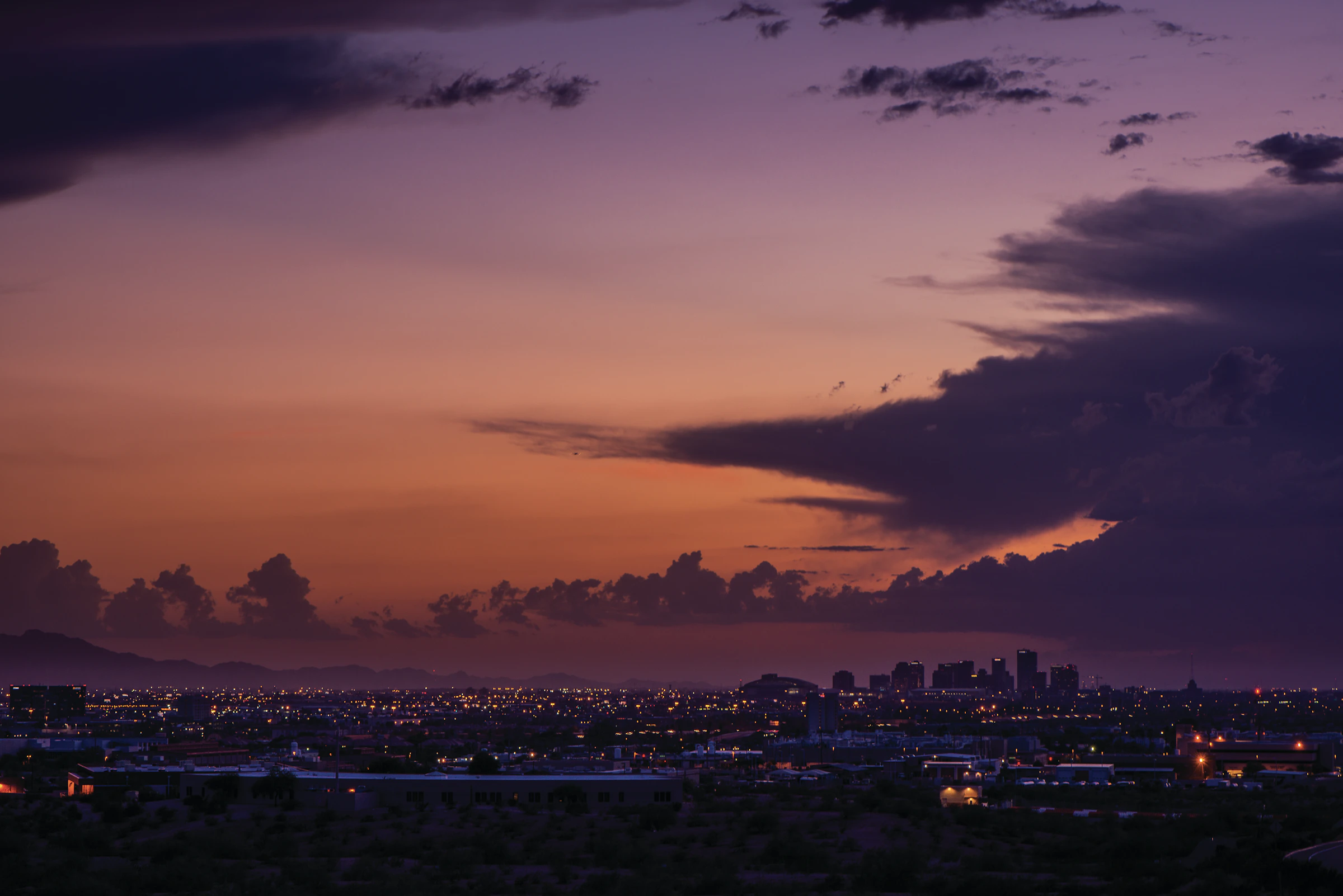 Downtown Phoenix skyline at dusk beneath a clouded sky, used as an editorial visual