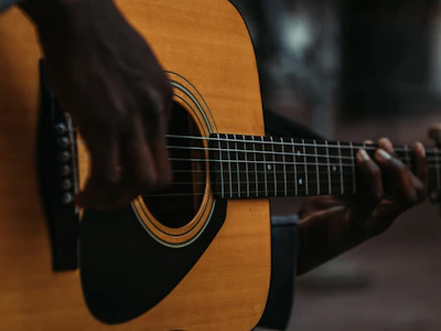 A close-up of a musician's hands playing an acoustic guitar under soft stage lighting.