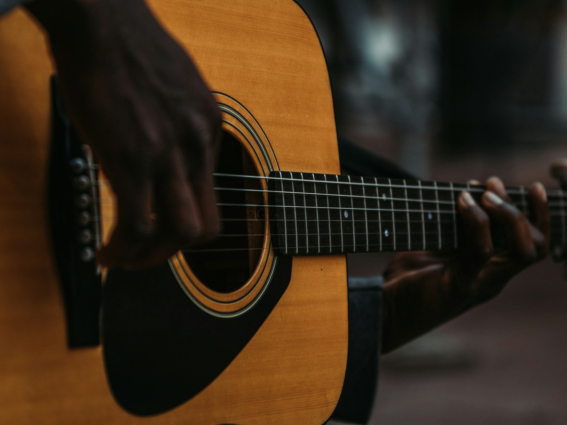 An intimate close-up of a musician playing guitar during a small event, highlighting emotion and detail.