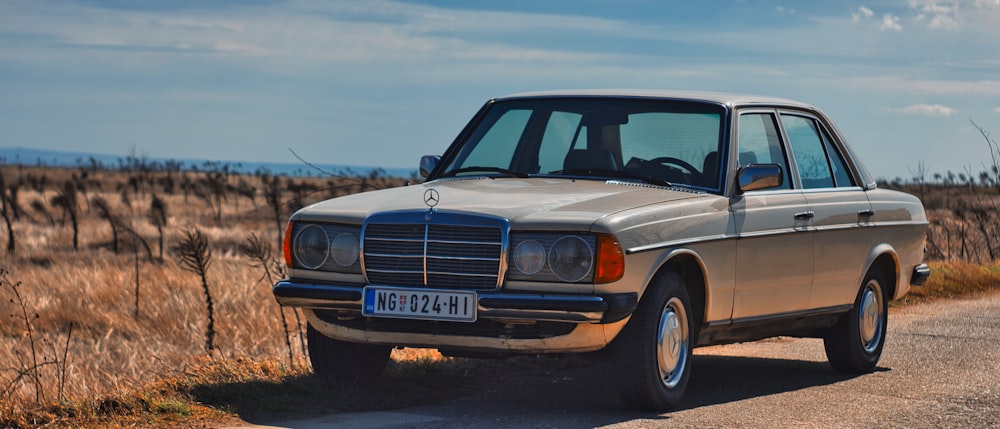 blue sedan on brown field during daytime