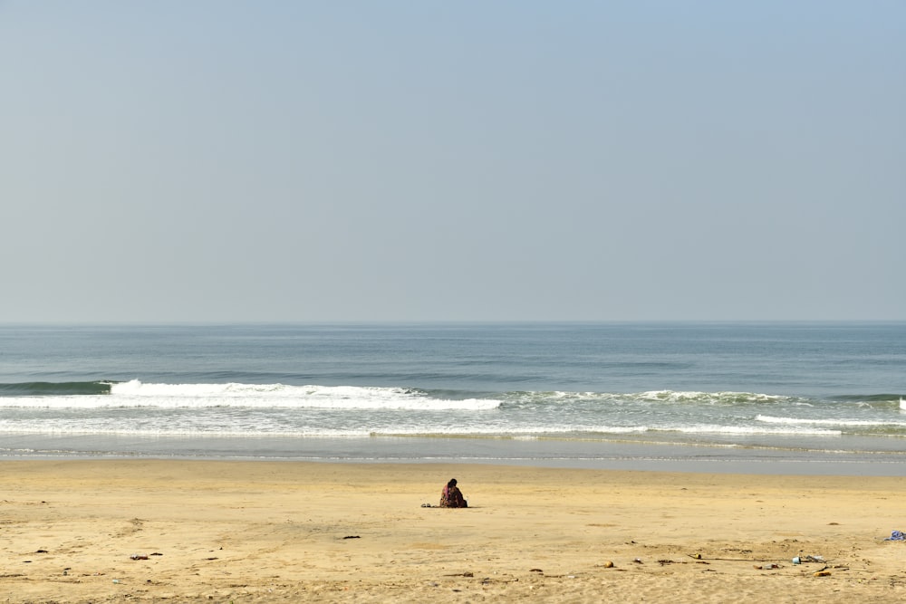person sitting on beach shore during daytime