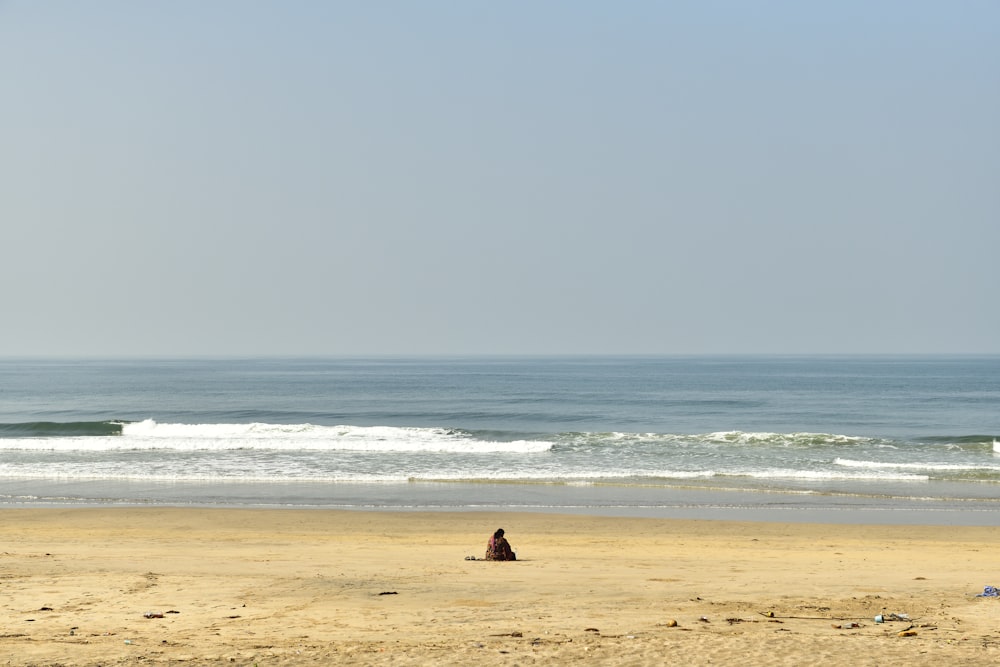 Persona sentada en la orilla de la playa durante el día