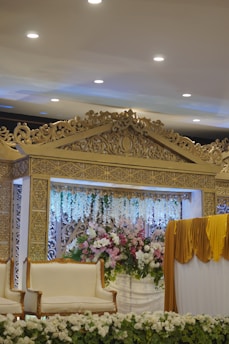 Elegant Haldi stage decorated with a mix of fresh flowers and draped fabrics in warm hues.