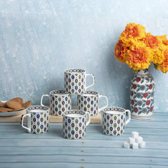 Close-up of colorful custom mugs with intricate designs, arranged on a bright table.