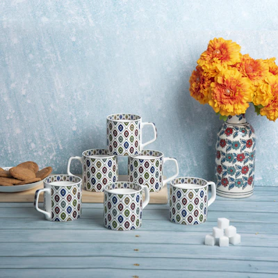 A set of vibrant ceramic mugs with playful patterns, arranged on a cozy linen cloth.