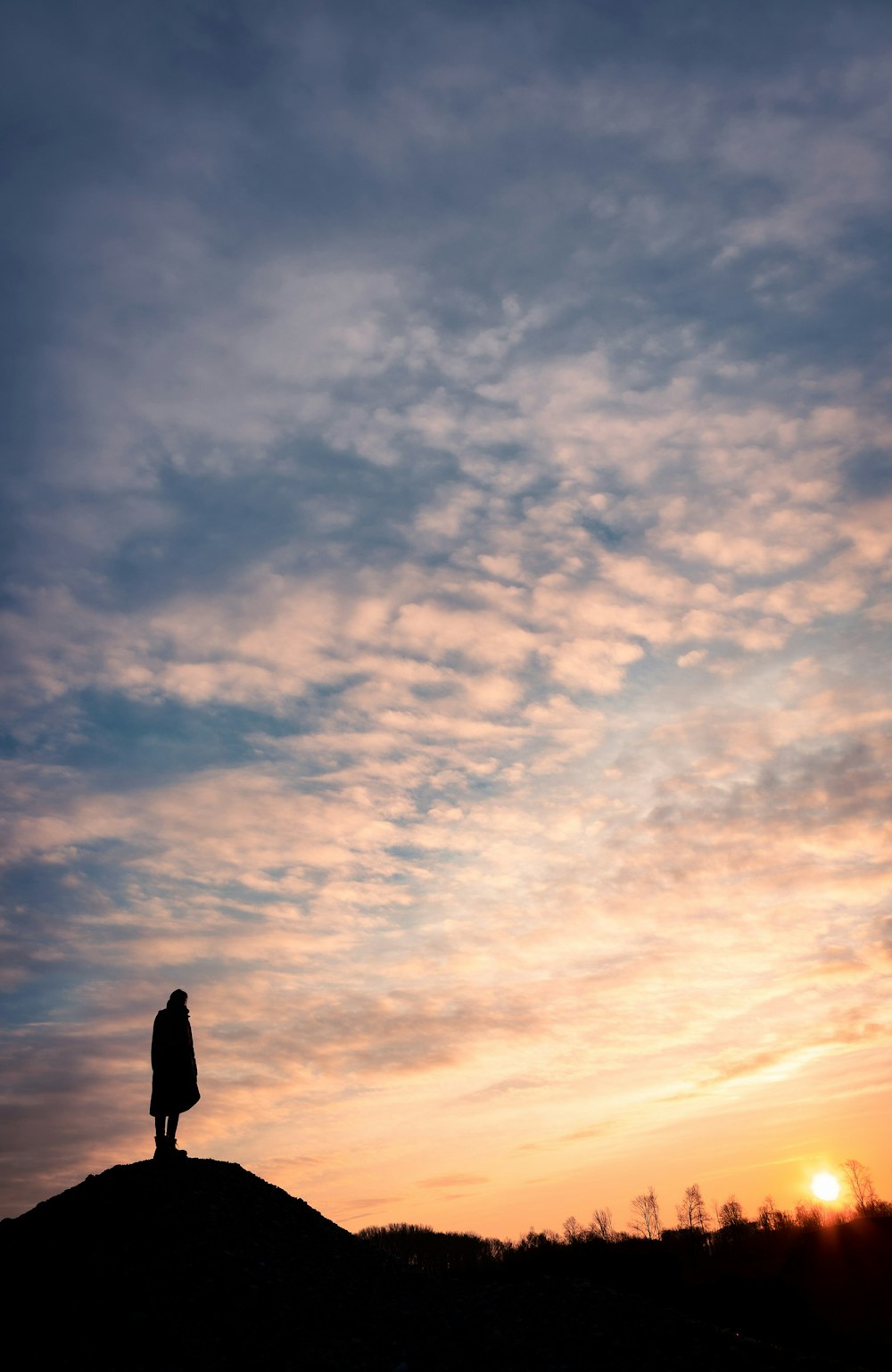 silhouette of man standing under cloudy sky during daytime