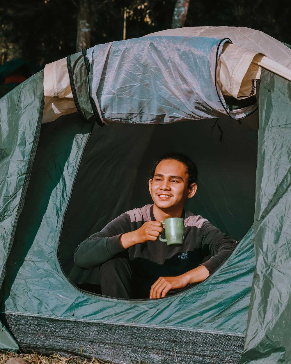 woman in black long sleeve shirt sitting on green tent