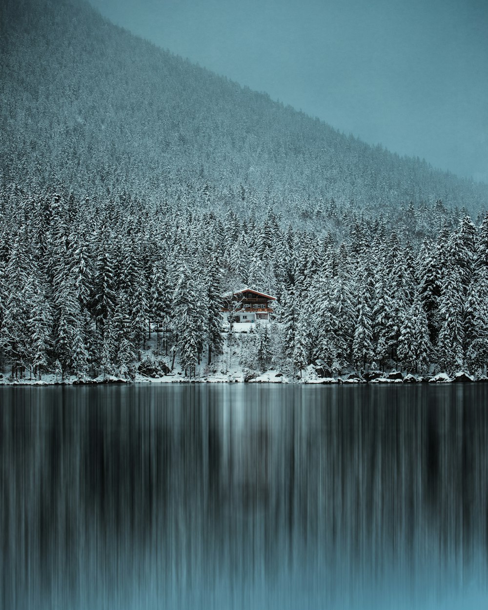 brown house on snow covered ground near body of water during daytime