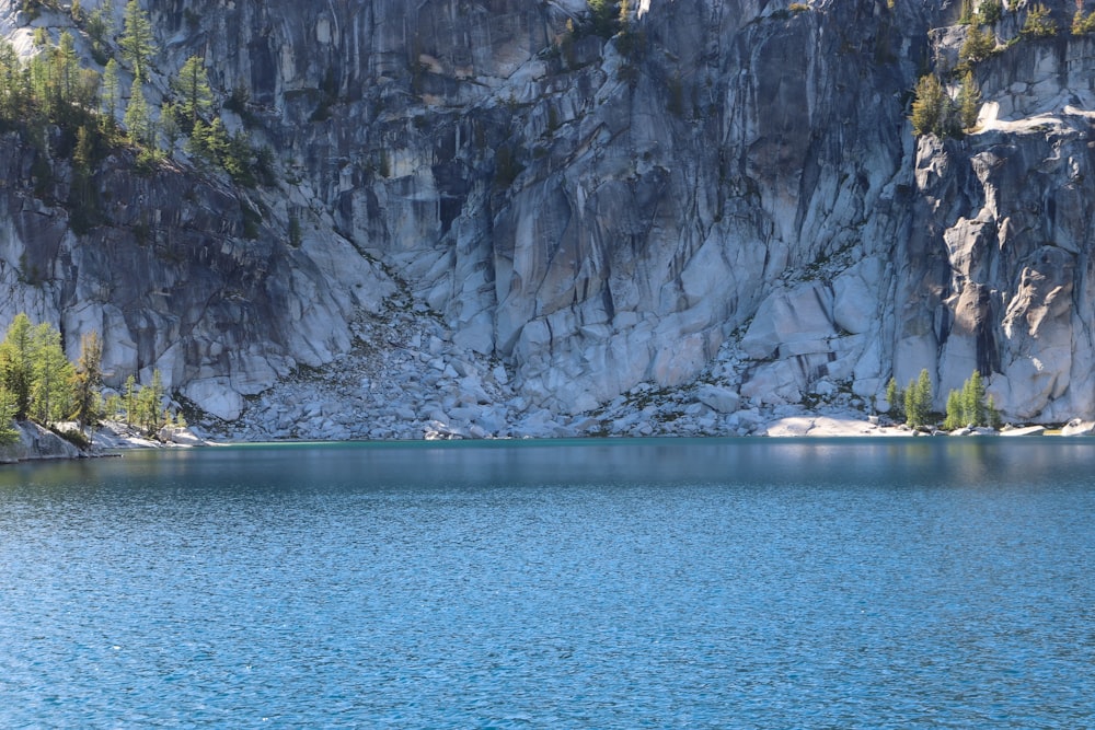 gray rocky mountain beside body of water during daytime