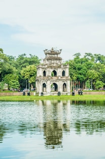 white concrete building near green trees and river during daytime