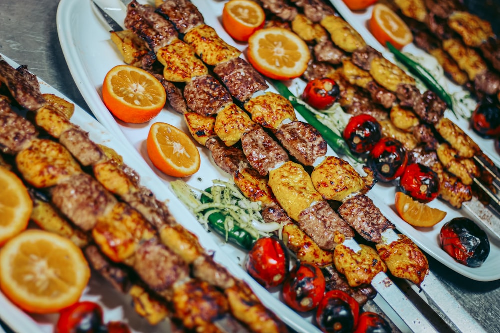 Viande grillée avec tranches d’orange et de légumes verts sur assiette en céramique blanche