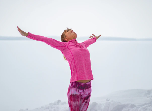 girl in pink long sleeve shirt and purple pants standing on white snow covered ground