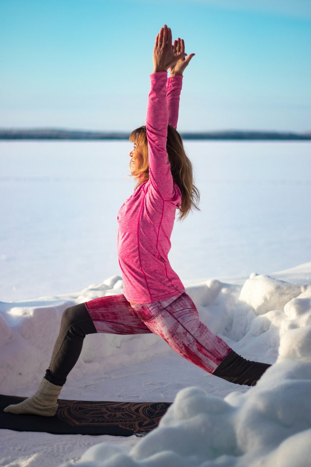 woman in pink jacket and black pants jumping on snow covered ground during daytime